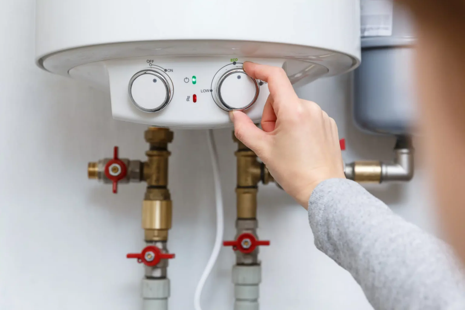 Homeowner adjusting the temperature controls on a water heater in Holladay